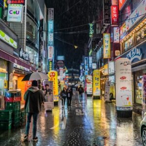 Colorful neon-lit street in Seoul, South Korea showing bustling nightlife with reflections on wet pavement.