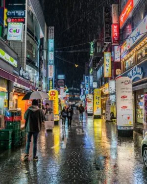 pexels-photo-2246789-2246789 Colorful neon-lit street in Seoul, South Korea showing bustling nightlife with reflections on wet pavement.